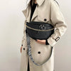 A beige trench coat features a black woven pattern waist bag with gold chain detailing and a patterned strap.
