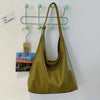 A olive green PU leather slouchy hobo shoulder bag hanging on a metal rack.