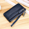 A dark navy genuine leather wristlet clutch wallet with a zipper closure resting on a wooden surface.