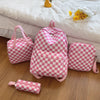 A pink and white checkerboard multi-pocket backpack is displayed on a wooden surface next to a small zippered pouch.