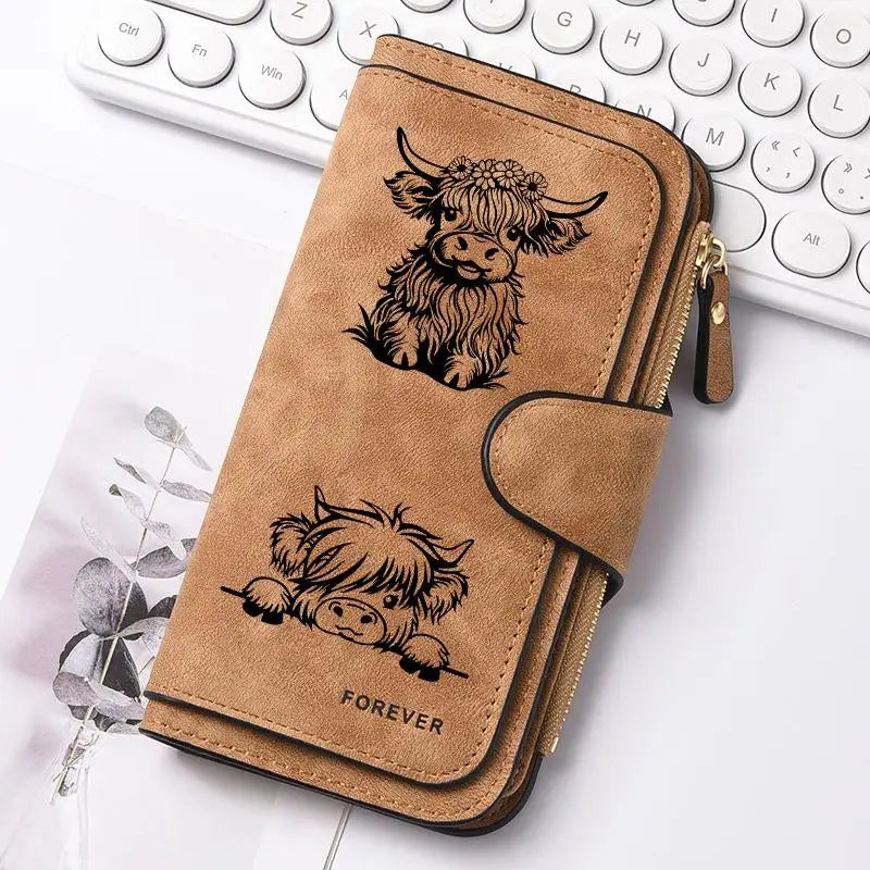 Cartera de cuero sintético marrón de vaca con cierre de cremallera y diseño de vaca grabado.