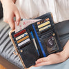 Eine Hand hält eine schwarze Lederclutch mit Kreditkarten und einem Ausweis.