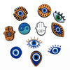 A collection of decorative shoe charms and pins featuring various eye and hand symbols in orange, blue, and black.