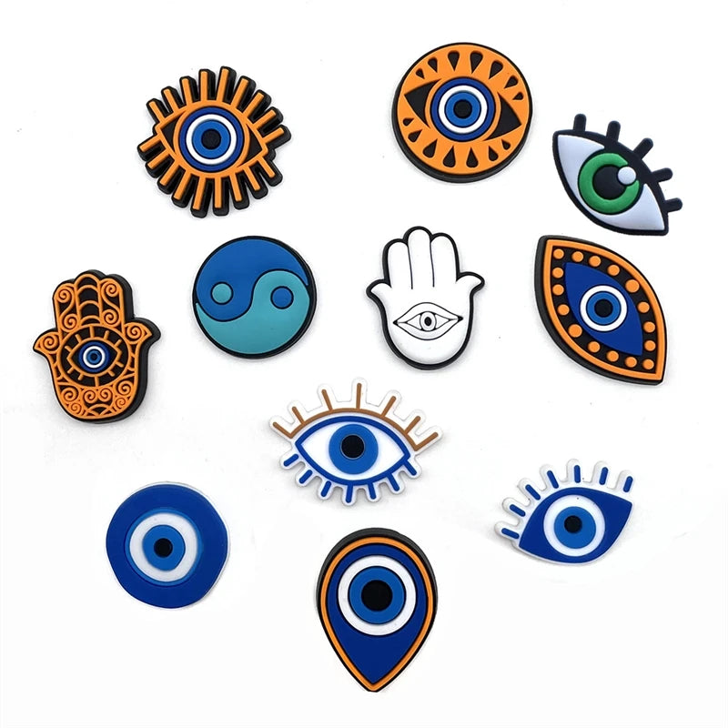 A collection of decorative shoe charms and pins featuring various eye and hand symbols in orange, blue, and black.