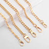 Several gold-colored adjustable metal chain handbag straps laid out on a white surface.