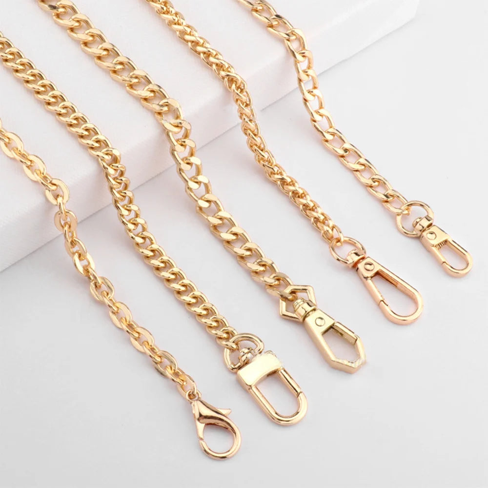 Several gold-colored adjustable metal chain handbag straps laid out on a white surface.