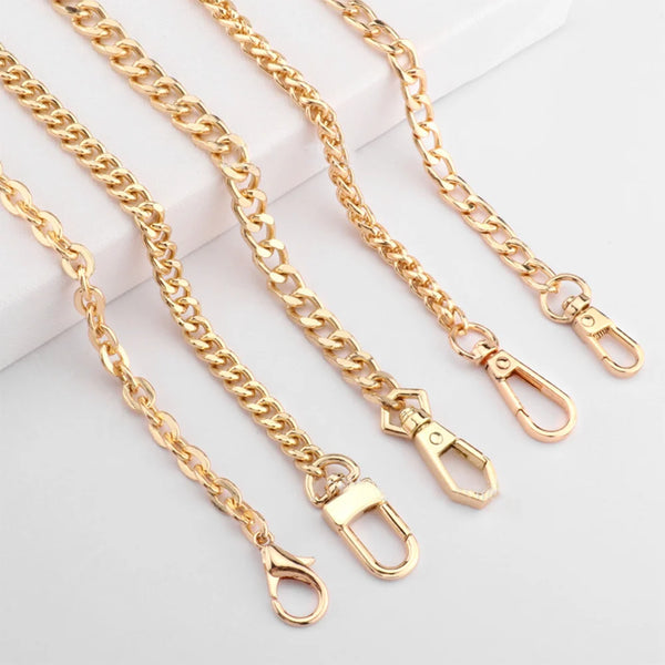 Several gold-colored adjustable metal chain handbag straps laid out on a white surface.