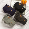 Eine Sammlung warmer, gestrickter Fingerlose Handschuhe in Dunkelviolett, Schwarz und Grau neben einer orangen Kugel.