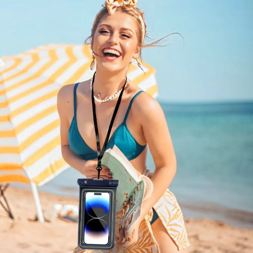 A smiling woman wearing a turquoise bikini and straw hat on a beach holding a waterproof phone case.