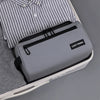 A gray travel toiletry bag is shown inside a white case, next to a striped shirt.