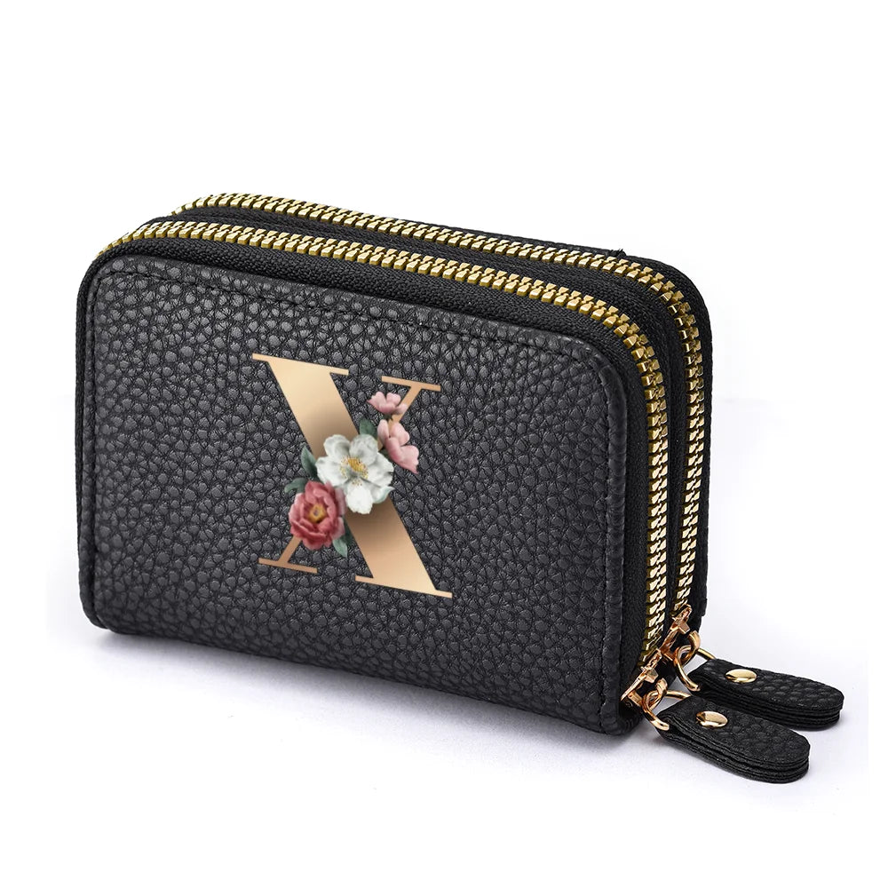 Black mini wallet with a gold letter X and floral accents featuring a double zipper closure