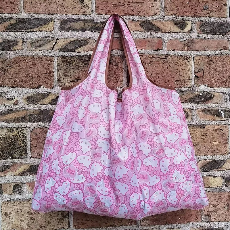 A pink and white patterned reusable shopping bag hanging against a brick wall.