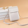 A white vintage PU leather crossbody bag with a light beige adjustable strap resting on a stack of white papers.