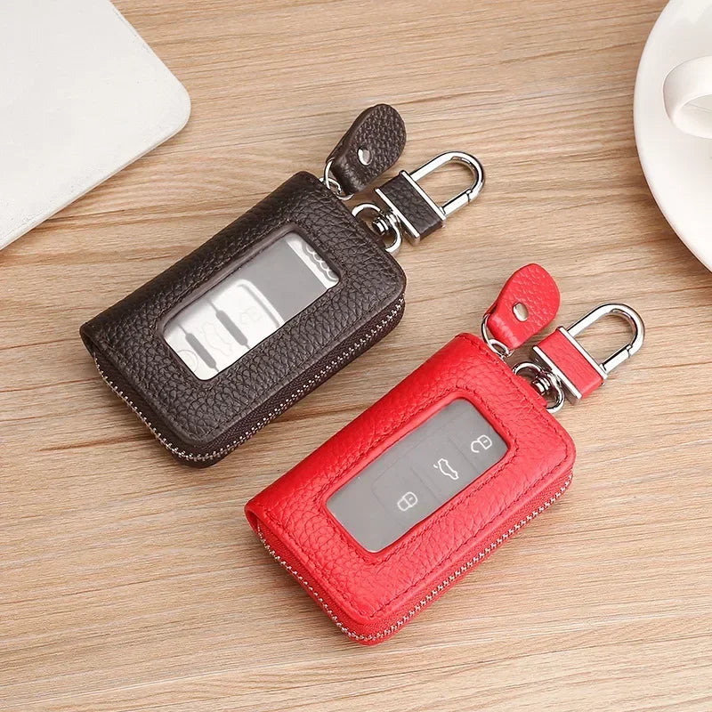 A red leather car key case with a transparent window and metal clasp is shown on a wooden surface.