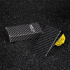 A black carbon fiber money clip is shown next to a yellow cord on a dark, textured surface.