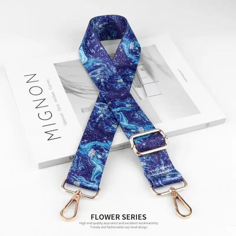 A dark blue and teal patterned nylon bag strap is displayed on a white box.