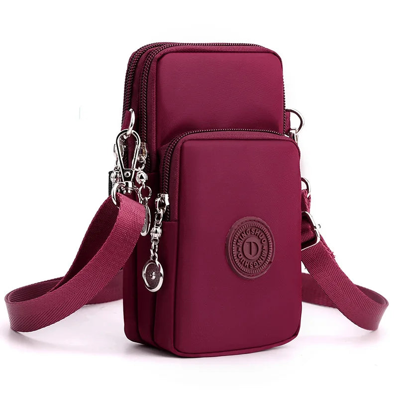 A deep magenta nylon crossbody phone bag with a silver clasp and adjustable strap.