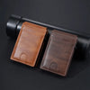 A brown PU leather card holder wallet is shown resting on a black cylindrical object.
