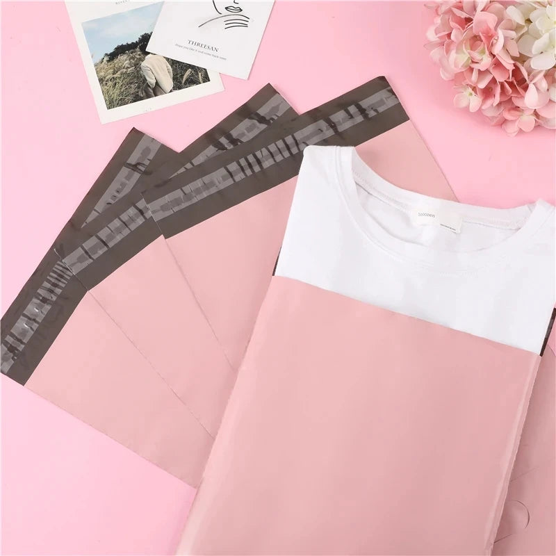 Bolsas adhesivas rosas para almacenamiento y envío, mostradas sobre un fondo rosa.