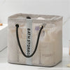 Organizador de bolsa de ducha de malla beige con asas negras y una correa blanca, mostrado sobre una superficie blanca.