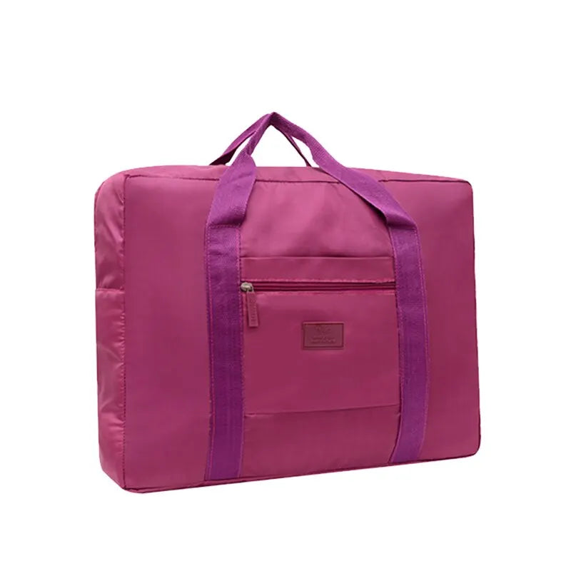 A magenta foldable travel duffel bag with a purple strap and pocket.