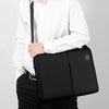 A black slim commuter laptop briefcase carried by a person wearing a white shirt and dark pants.
