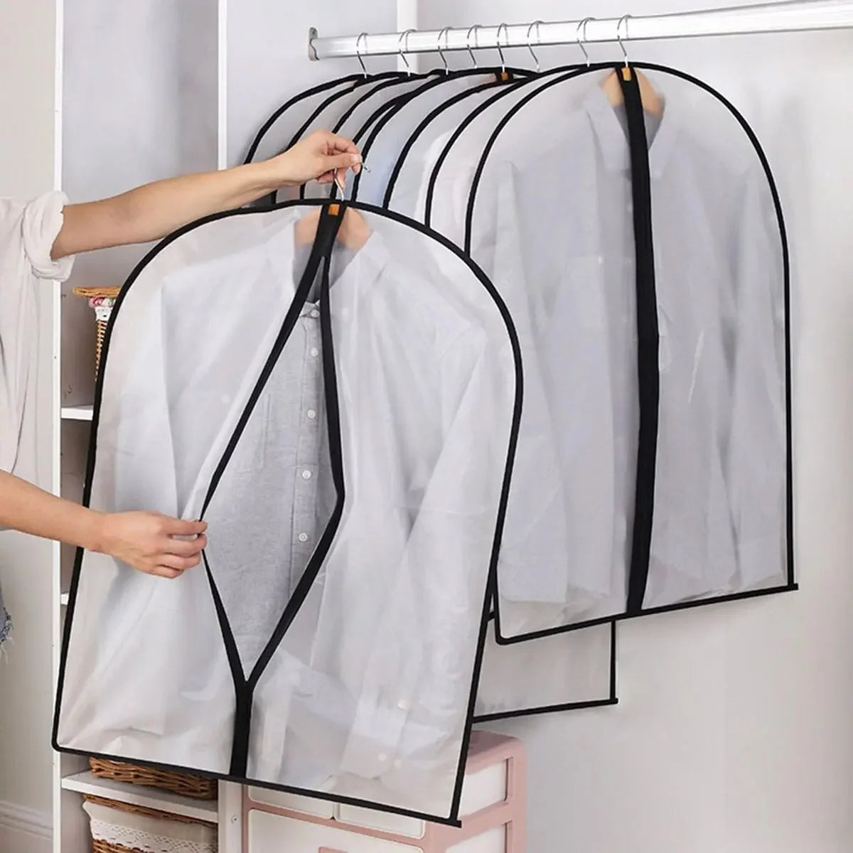 A white garment dust cover is being placed on a hanger, shown in a display of clear covers for clothing.