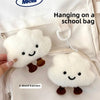 A white cloud-shaped plush keychain with embroidered features is hanging on a school bag.