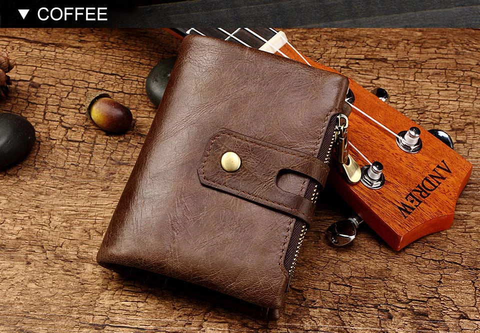 Braunes Leder-Zweisefalldertasche auf Holzoberfläche neben Gitarre und dunkle Früchte.