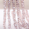 A close-up of pink AB faceted crystal glass beads in a wheel shape strung on a string.