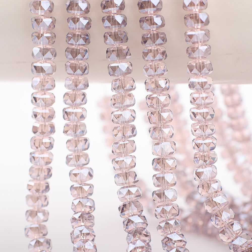 A close-up of pink AB faceted crystal glass beads in a wheel shape strung on a string.