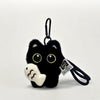 A black cat plush keychain featuring large yellow eyes and a white nose, attached to a black cord.