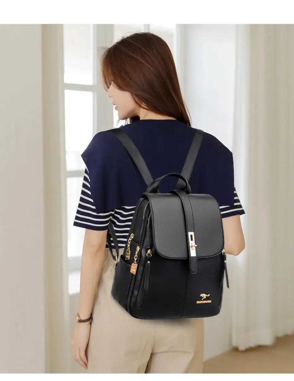 Une femme portant un haut bleu marine et un pantalon beige, vue de dos, portant un sac à dos en cuir microfibre noir.