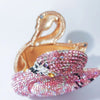 Pochette à clochette rose cristalline en forme de cygne avec des détails scintillants iridescents.