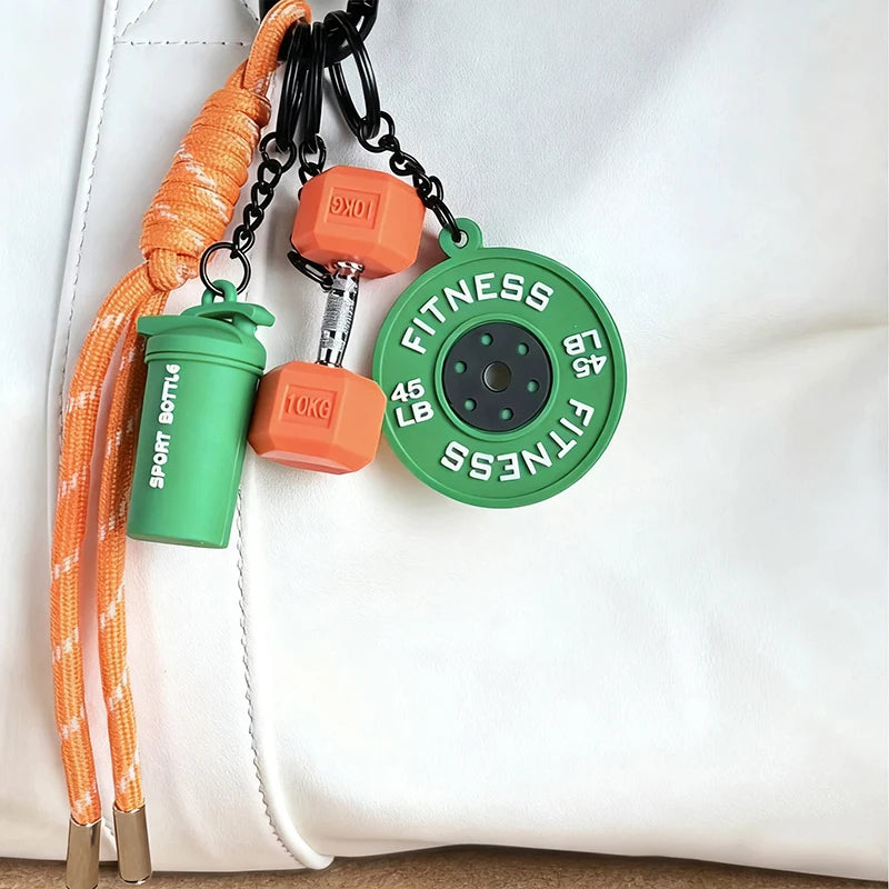 Orange nylon fitness keychain with a green bottle holder and an orange weight, attached to a white leather surface.