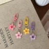 A collection of colorful resin flower keychains in pink, yellow, and purple hanging from metal rings.