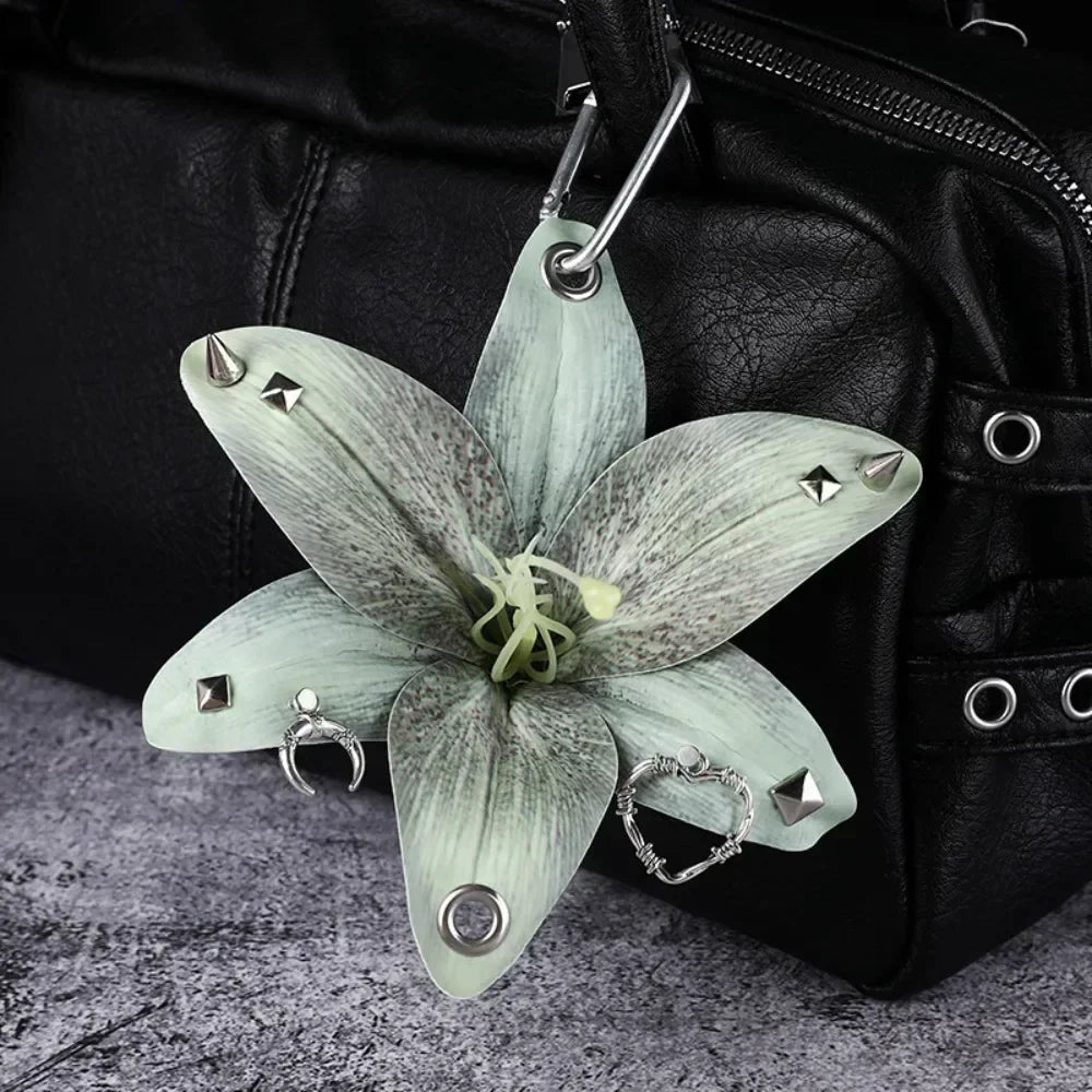 A realistic pale green orchid flower keychain attached to a black leather bag.