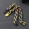 A close-up of a chunky Cuban link bracelet featuring gold and black metal links.