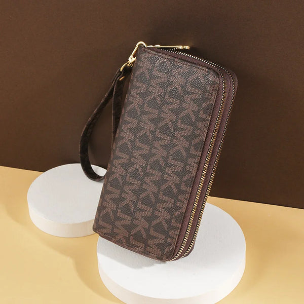 A brown patterned PU leather zippered wallet resting on a white cylindrical stand.