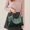 A woman holds a dark green leather casual crossbody shoulder bag with a zip closure.