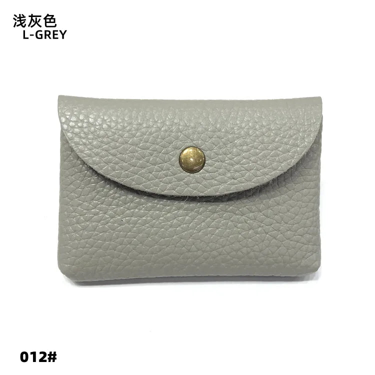 A light grey genuine leather card holder or coin purse with a gold-toned stud closure.