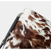 A close-up of a brown and white spotted cowhide leather crossbody bag.