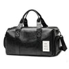 Black leather duffle bag with padded straps and a small white label on the front