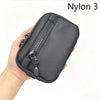Une main tient une pochette noire en Nylon 3 avec fermeture éclair, conçue pour les clés et les essentiels.