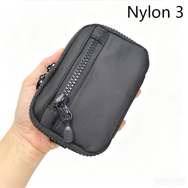 Une main tient une pochette noire en Nylon 3 avec fermeture éclair, conçue pour les clés et les essentiels.