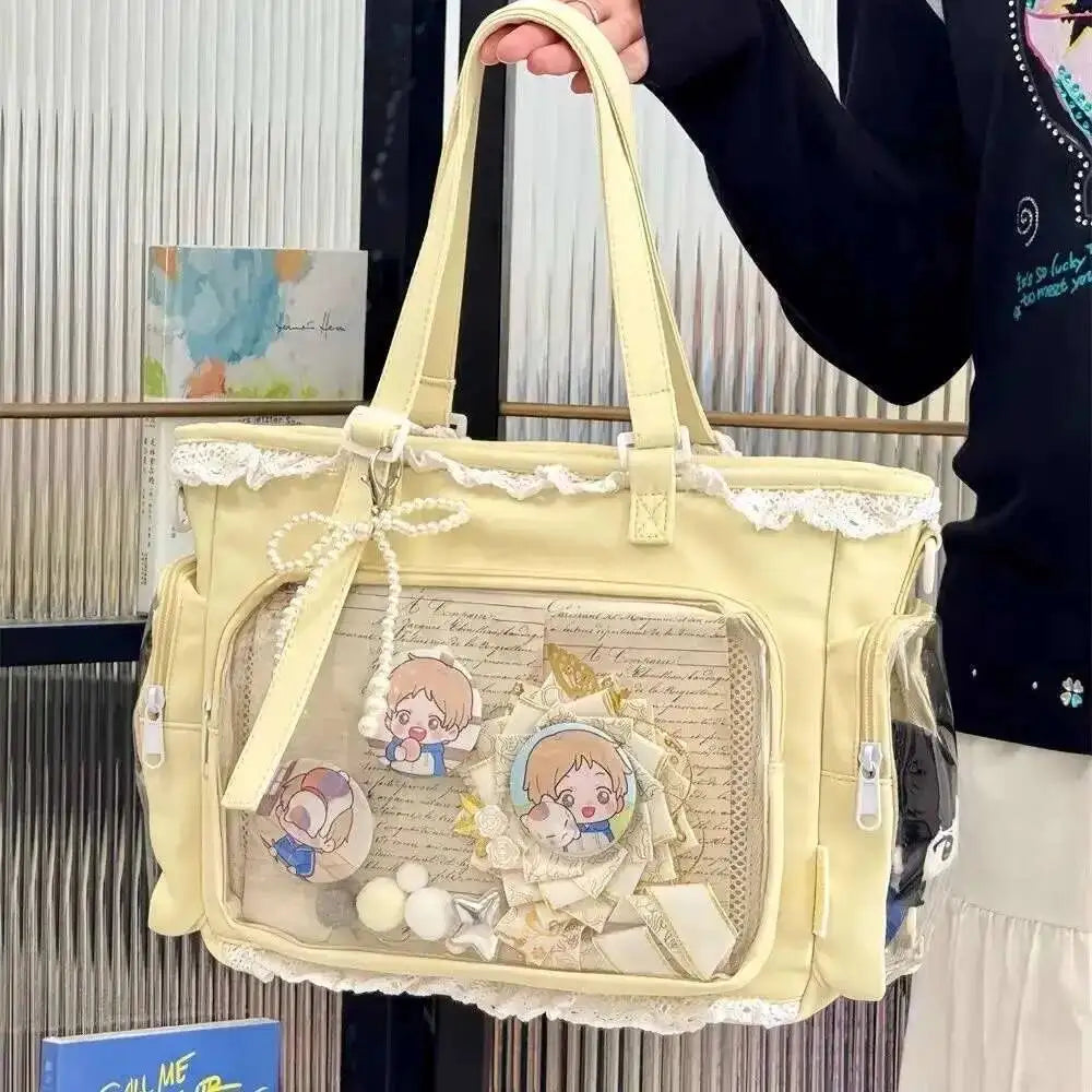 A light yellow transparent shoulder tote bag with lace trim and decorative elements is being held by a person.