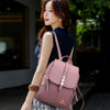 Une femme portant un sac à dos en cuir microfibre brun rose vintage et un haut bleu foncé, debout à l'extérieur.