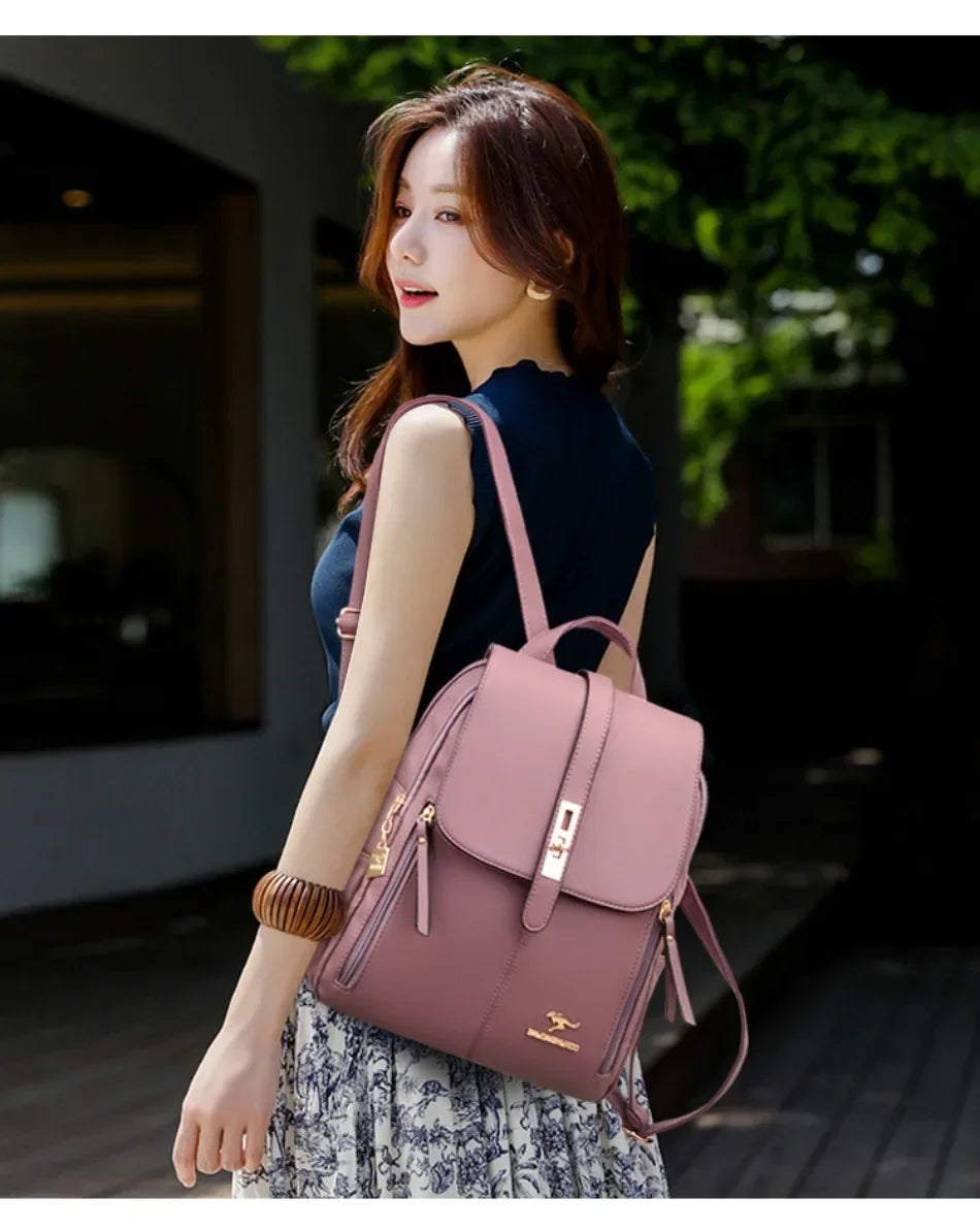 Une femme portant un sac à dos en cuir microfibre brun rose vintage et un haut bleu foncé, debout à l'extérieur.