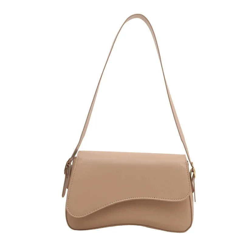 A tan vintage curved flap shoulder bag made of soft faux leather with a long strap.