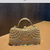 An elegant diamond rhinestone evening clutch bag with a golden tassel displayed on a brown surface.